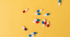 - Tennessee Behavioral Health Assorted blue, white and red capsules scattered on a yellow background.