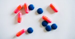 - Tennessee Behavioral Health Assorted pharmaceutical pills: pink capsules and blue round tablets scattered on a white surface on a plain background.
