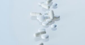 - Tennessee Behavioral Health Assorted white pills and capsules scattered on a reflective light-blue surface.