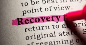 Close-up of the word 'Recovery' highlighted in pink on a dictionary page in black ink text behind it.] , not good