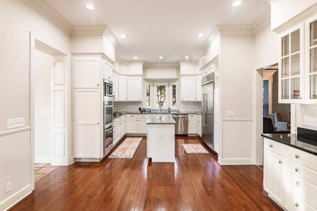 tbh-addiction-treatment-center-kitchen2 - Tennessee Behavioral Health Bright white kitchen with granite island, stainless steel appliances, and dark hardwood floors.