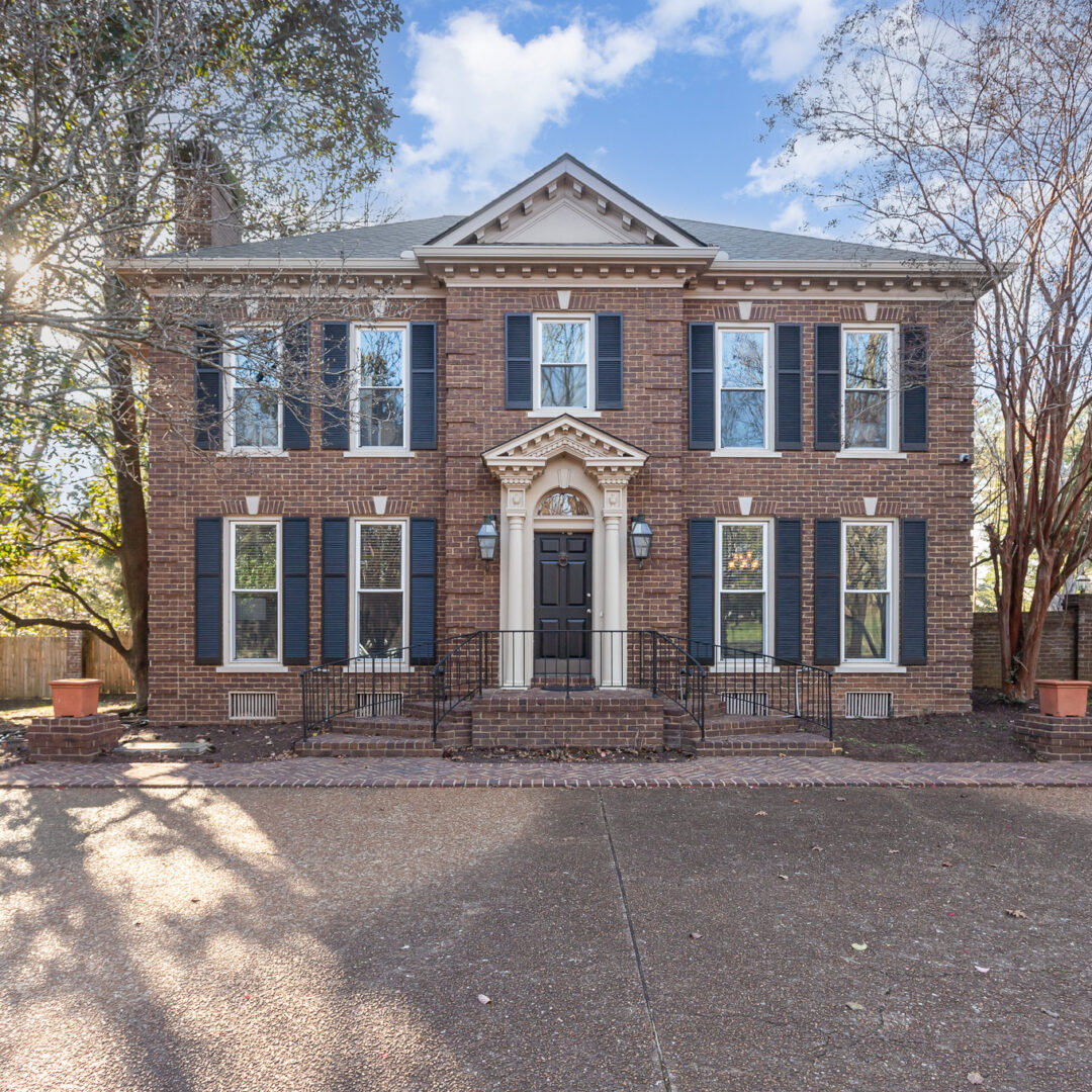 005_ndp-120623-e-00-edit Home exterior: Two-story brick house with black shutters, symmetrical design, and landscaped front yard. Real estate architecture.